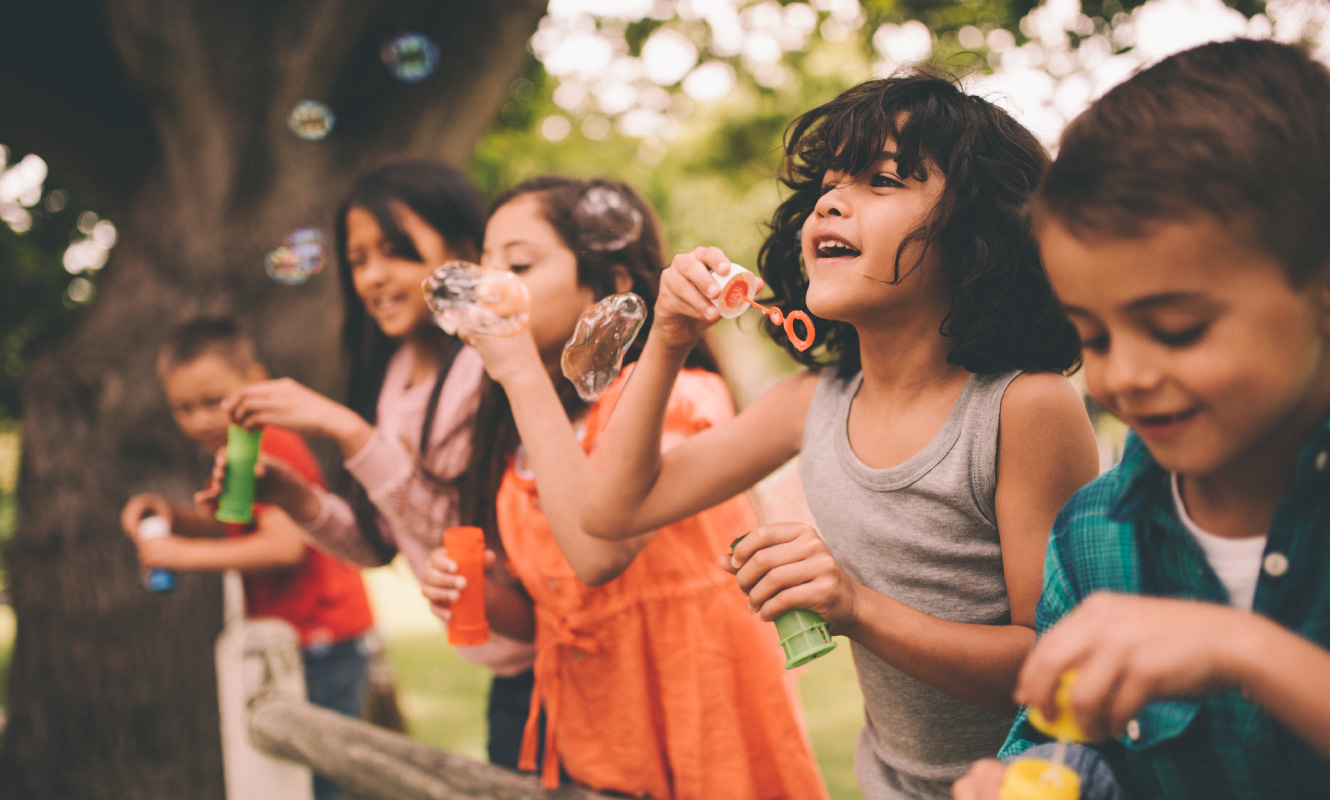 A group of diverse children playing and blowing bubbles