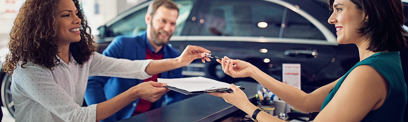 A woman at a car dealership signing paperwork