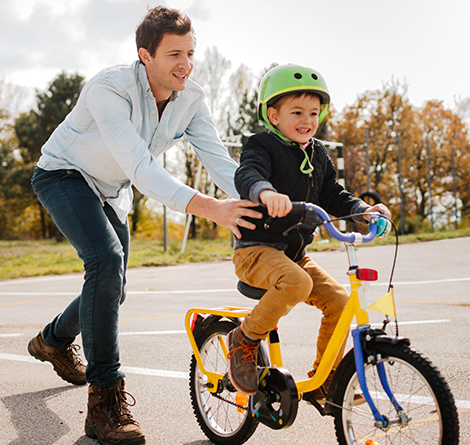 A dad teaching his son how to ride a bike