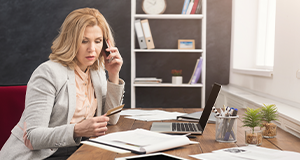 Woman at desk on phone holding credit card