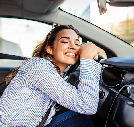 A woman hugging her steering wheel inside her car