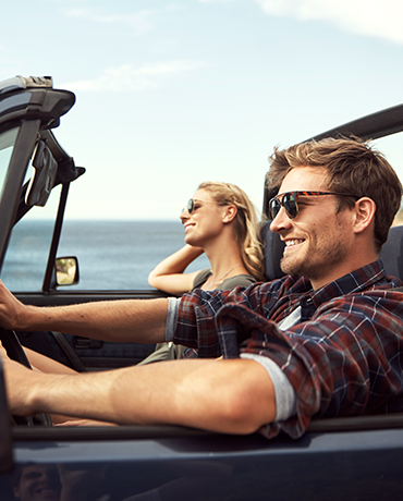 couple in convertible next to ocean