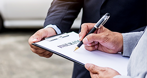 man signing paper on clipboard