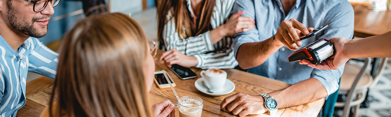 four people at restaurant paying by scanning phone