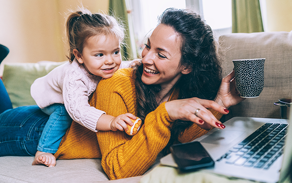 woman with little girl on her back working on laptop