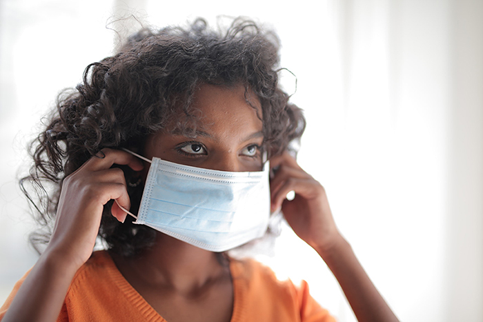 Young woman putting on facemask