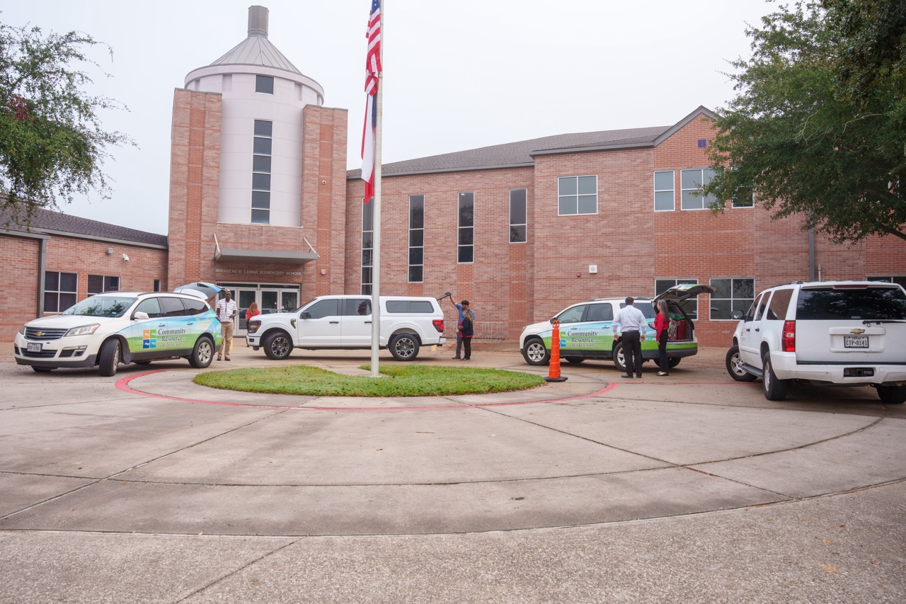 Community Resource Credit Union employees and cars parked outside of a school.
