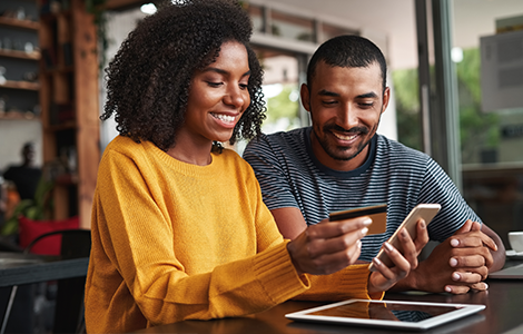 couple using phone with credit card in hand