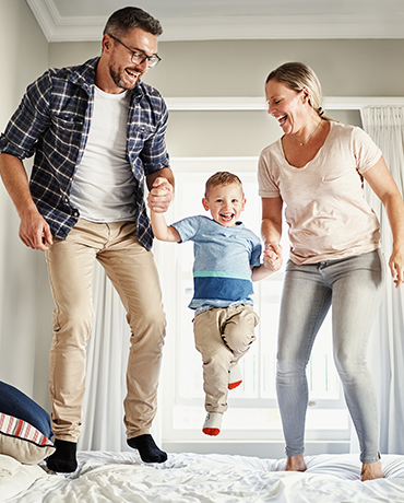 Family laughing and jumping on bed