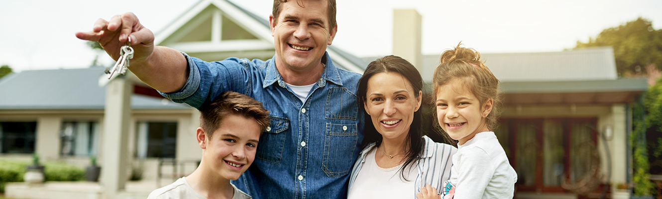 family posing in front of thier new house