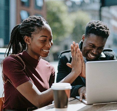 man and woman giving each other a high five while looking at laptop