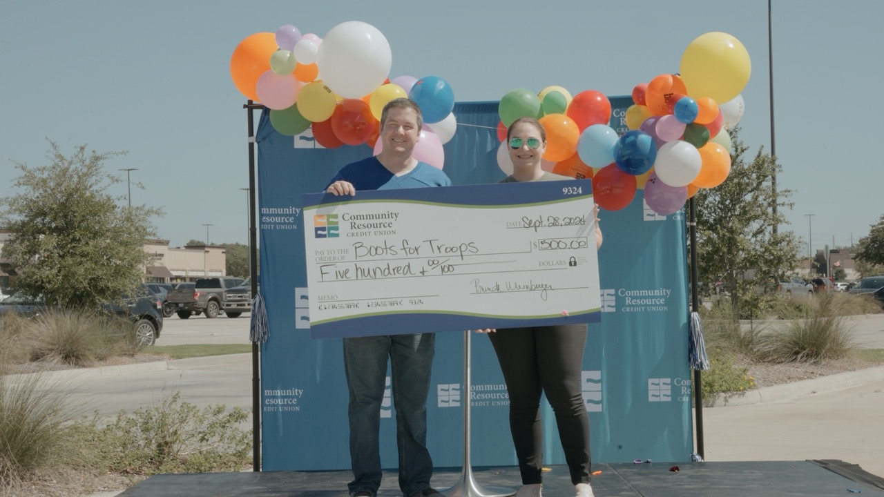 Community Resource Credit Union employees holding a check from Boots for Troops.