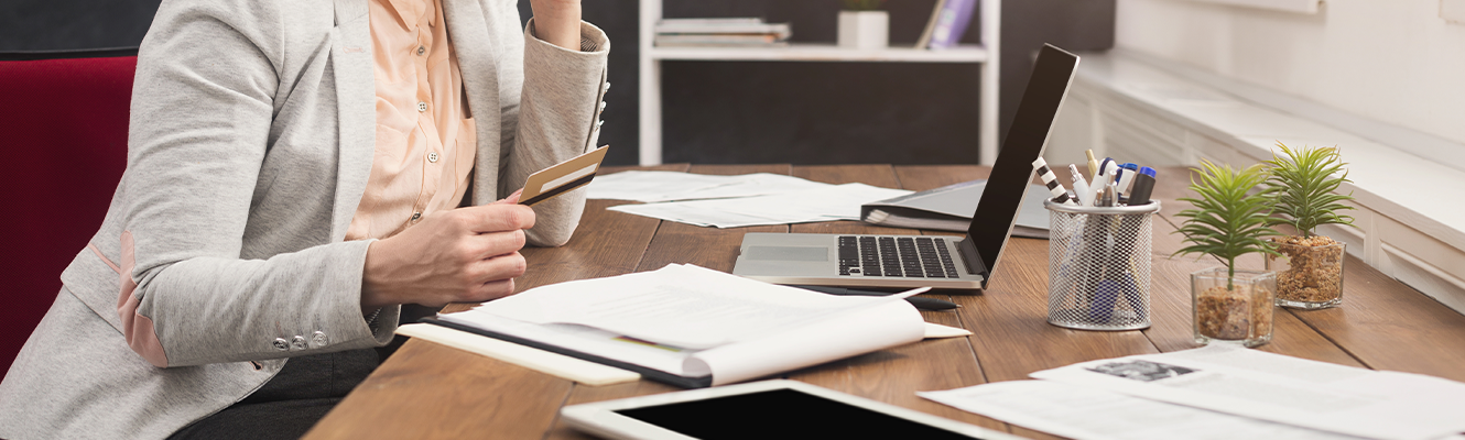 woman at desk holding credit card