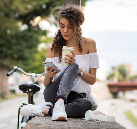 woman outside on phone with coffee