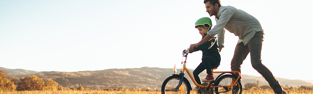 dad teaching son how to ride a bike