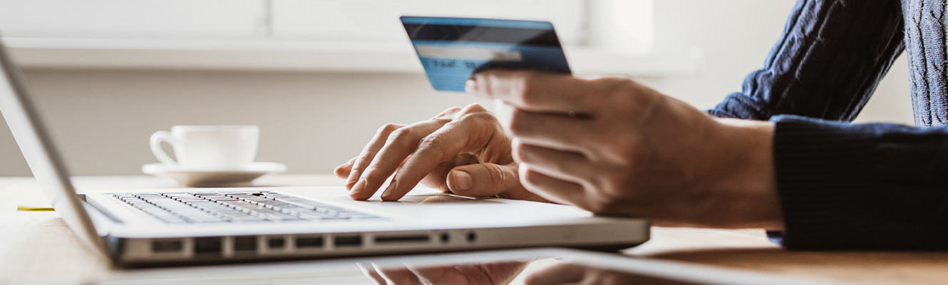 person on laptop holding credit card