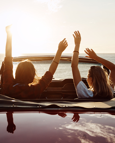 couple in convertible with hands up