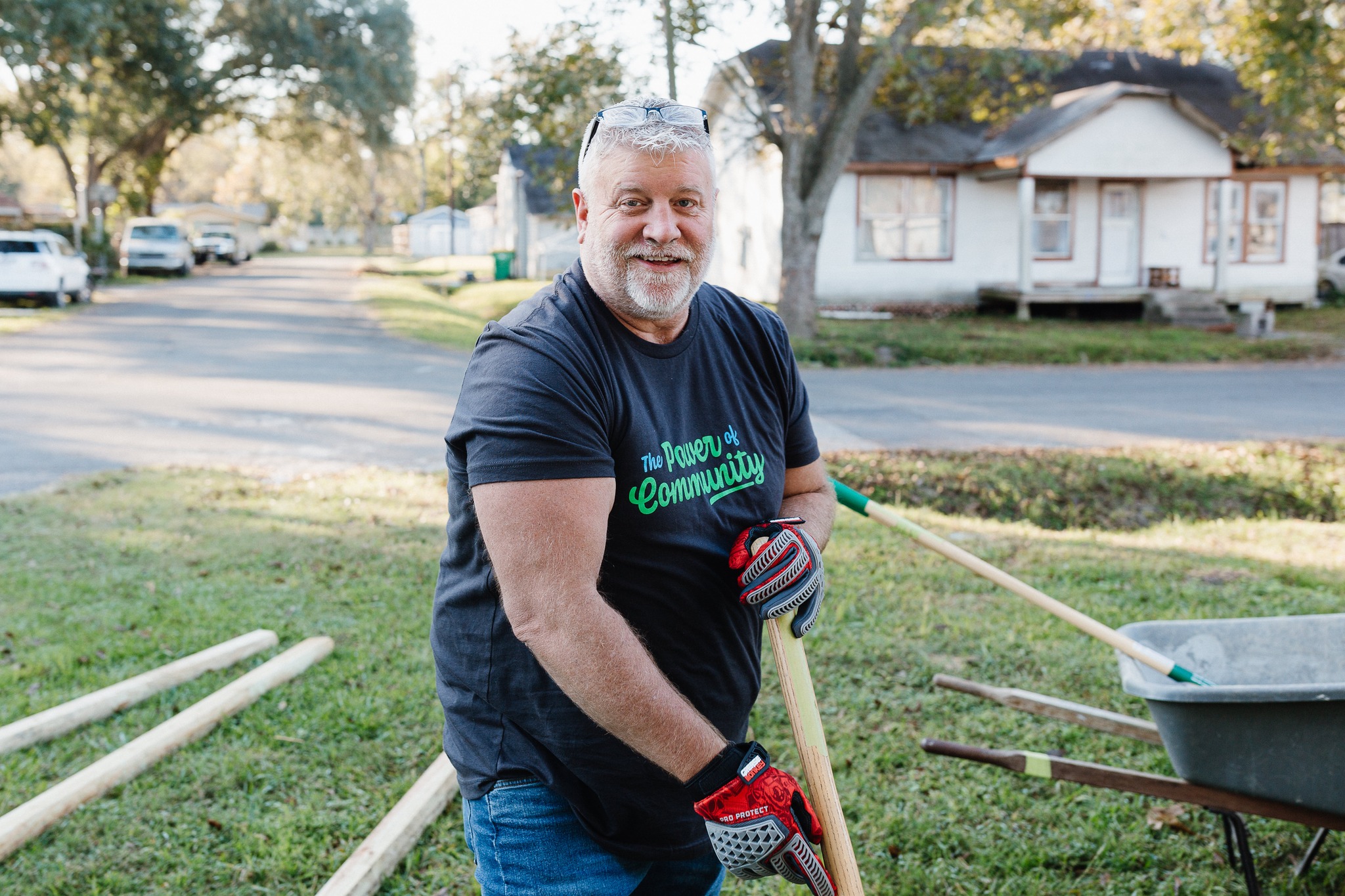 A man outside in a neighborhood doing yard work.