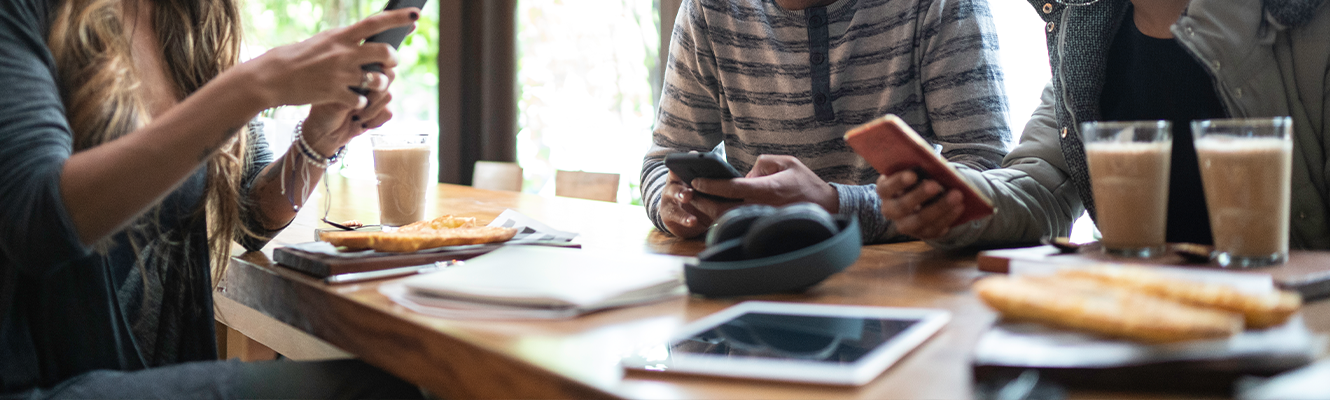 group of people around table looking at phones