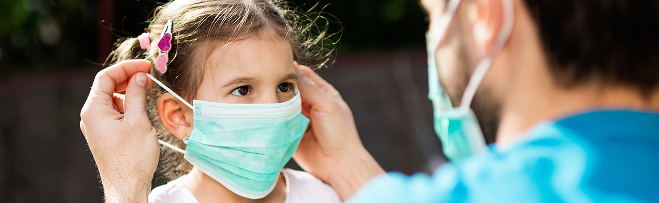 Dad placing facemask on young girl