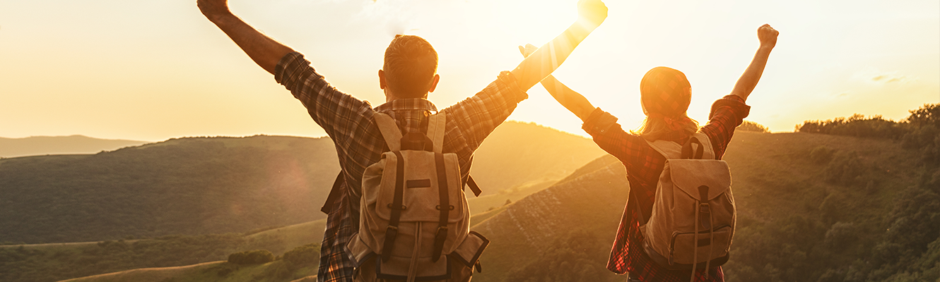 two hikers with hands up