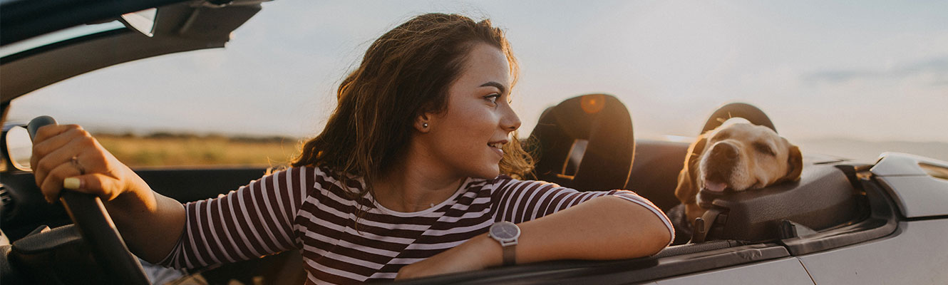 A woman driving a car with her pet dog