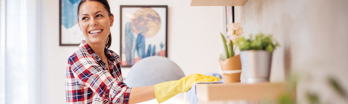 A woman in her home wearing gloves and cleaning.
